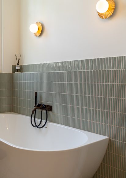 Vrijstaand bad met groene verticale tegels, gouden Nuura wandlampen en Hotbath bronzen kraan, badkamerontwerp atelier Det Wageningen