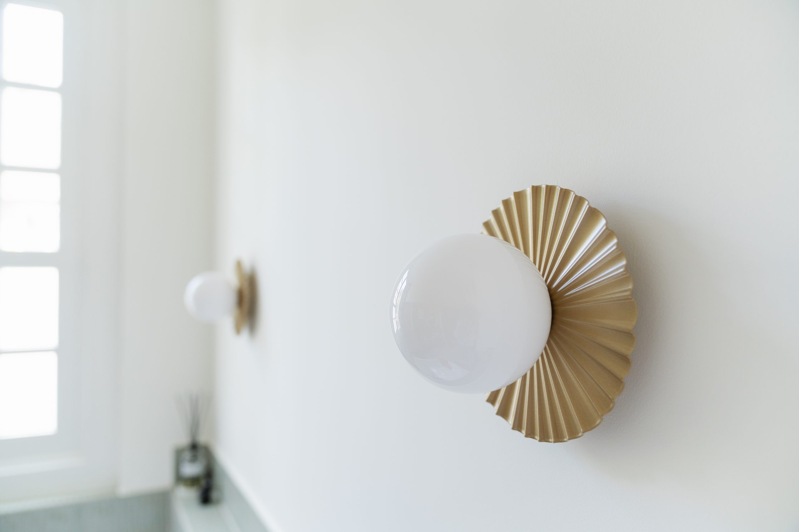 Detail Nuura gouden wandlamp met natuurlijk licht vanuit klassiek raam, sfeerbeeld badkamer atelier Det Wageningen