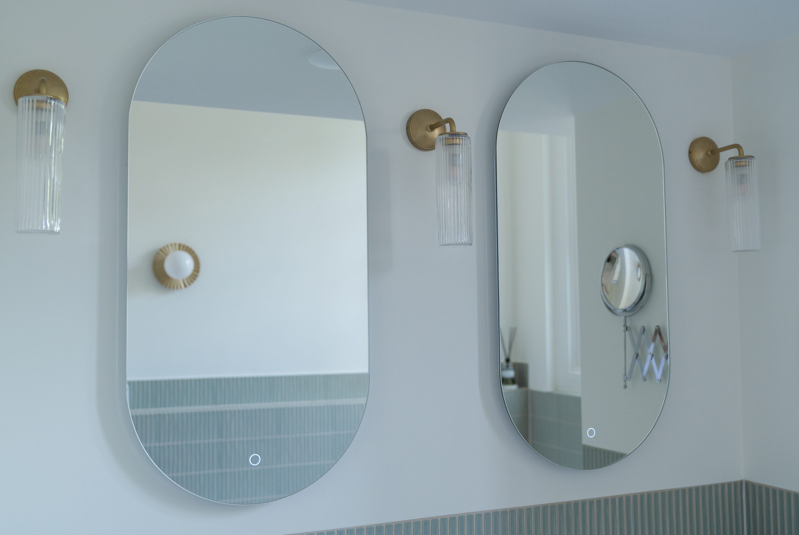 Ronde badkamerspiegels met Corston wandlampen geribbeld glas en gouden armatuur, reflectie groene verticale tegels, badkamerontwerp atelier Det Wageningen