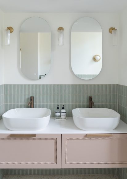 Dubbele wastafel met ovale spiegels, Corston wandlampen, groene verticale tegels en maatwerk wastafelmeubel met Decwood mouldings, badkamerontwerp atelier Det Wageningen