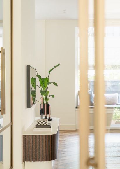 Interieur hoekhuis Rotterdam - doorkijkje hal naar woonkamer met maatwerk tv-meubel en bronzen aluminium schuifdeur