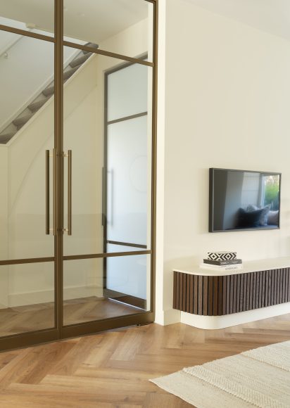 Interieurontwerp woonkamer met zwevend maatwerk tv-meubel, bronzen aluminium schuifdeur en visgraat pvc vloer